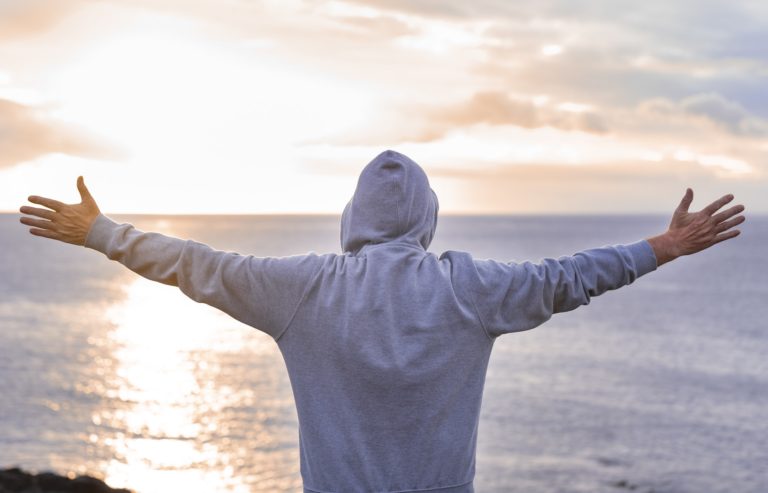 Tourist stands on cliff in front to the ocean in a winter day enjoying the infinite and freedom